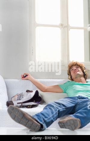 Young man with headphones lays on couch Stock Photo