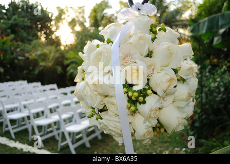 A flower bouquet with roses in front of rows of chairs at a wedding ceremony Stock Photo