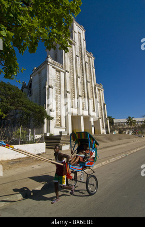 Man with a rickshaw in front of a modern church in Mahajanga, Madagascar, Africa Stock Photo