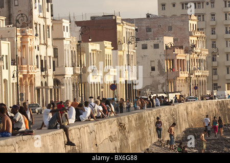 Crowds of people sitting on sea wall on the Malecon, in Havana, Cuba, West Indies, Central America Stock Photo
