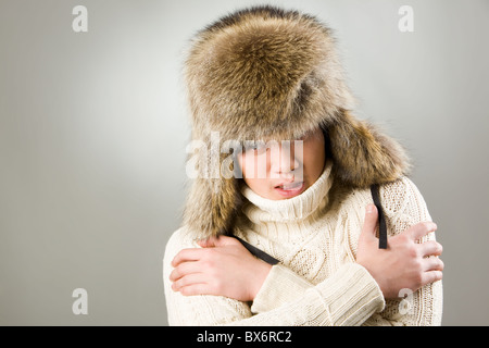 Portrait of man in warm fur hat and knitted sweater showing coldness Stock Photo