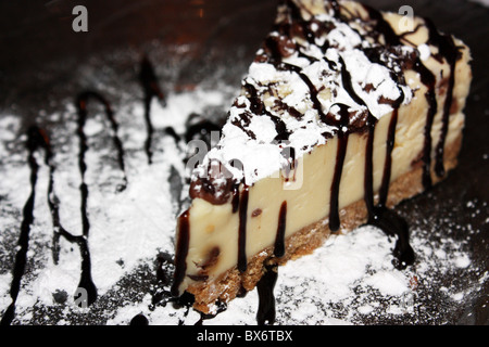 A slice of New York style cheesecake drizzled with chocolate sauce Stock Photo