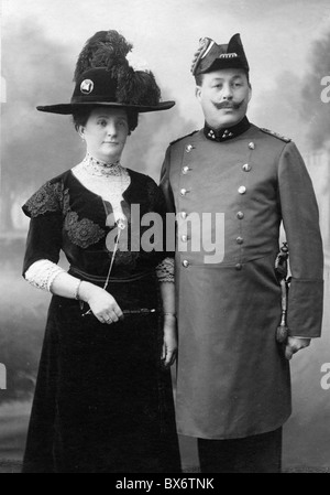 people, couples, 1900 - 1930, smartly dressed couple with man in uniform of a civil servant, circa 1900, Germany, German Empire, half length, standing, clothes, outfit, outfits, fashion, hat, hats, feather, feathers, bicorn, moustache, mustache, moustaches, mustaches, uniform, uniforms, civil servant, civil servants, at the turn of the 19th / 20th century, festive, feastful, festal, couple, couples, historic, historical, woman, women, female, man, men, male, people, 1900s, Additional-Rights-Clearences-Not Available