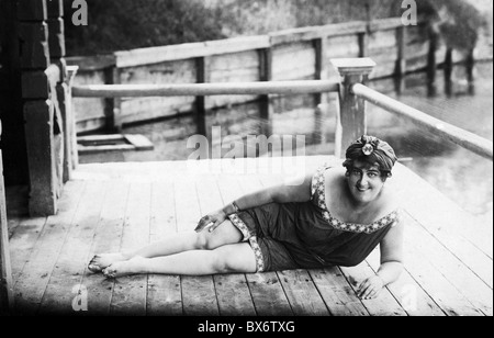 1920s WOMAN IN BATHING SUIT COSTUME STANDING ON BEACH PUTTING BAIT