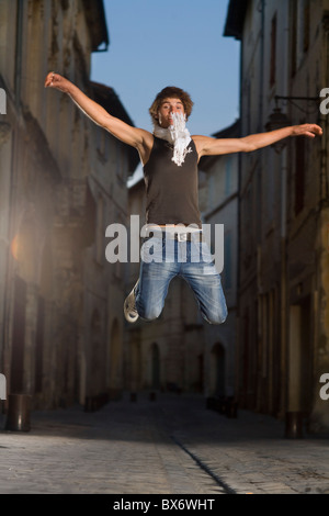 Young man jumps in street at dusk Stock Photo