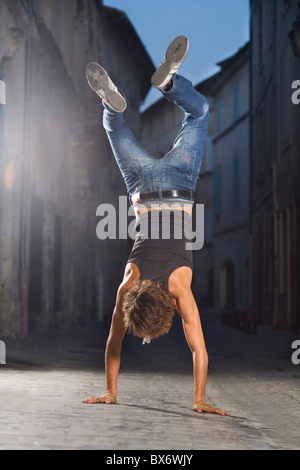Young man walks on hands in street Stock Photo