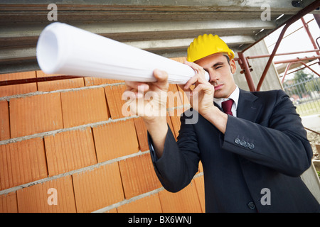 architect looking through scroll in construction site Stock Photo