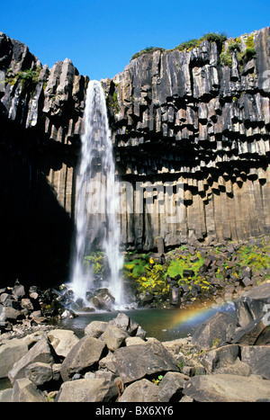 The Svartifoss waterfall in Skaftafell National Park, Iceland - with a little rainbow over the pond. Stock Photo