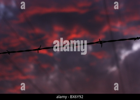 Barbed wire silhouetted against a dramatic sunset sky. Stanislaus county, California USA Stock Photo