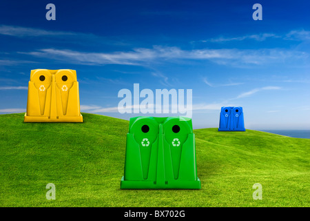 Recycle containers for glass, metal, plastic and paper waste placed on a green meadow landscape Stock Photo