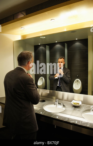 Confident businessman in front of mirror restroom/public toilet Stock Photo