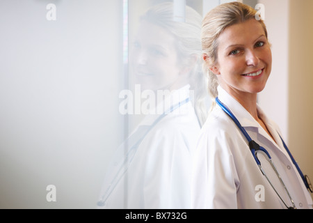 Doctor against a window, smiling Stock Photo