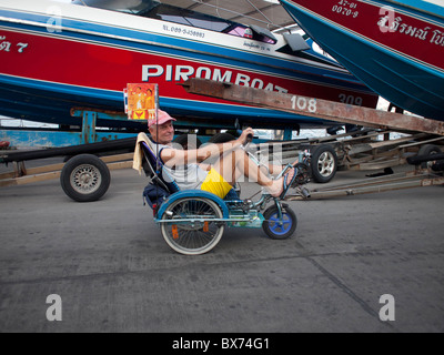 The old man riding his tricycle bicycle along Pattaya Bay Stock Photo