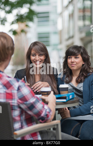 3 friends seated at cafe table Stock Photo