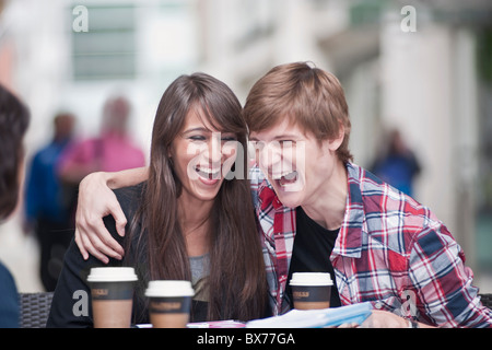 Couple seated at cafe table, laughing Stock Photo