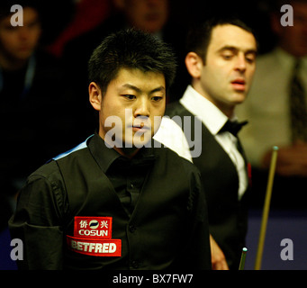 Liang Wenbo of China in action against Ronnie OSullivan of England, during the 1st Round of the Betfred World Snooker Champions Stock Photo