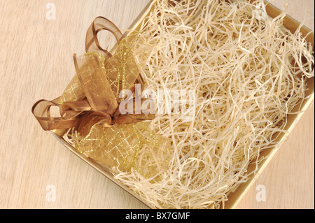 Open gift box and bow - filled with packing bast - detail Stock Photo