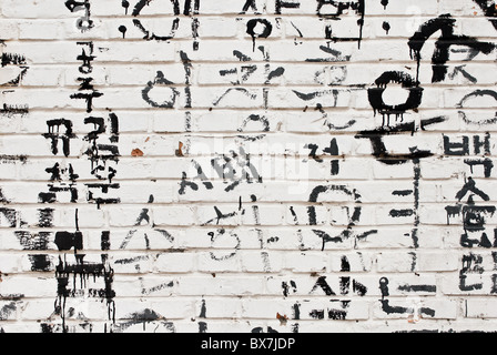 Detail of a bricks wall with random Korean characters painted on it Stock Photo