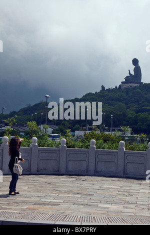 Hong Kong, Lantau island seated bronze statue the Big Buddha as one person looks on Stock Photo