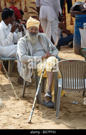 Indian man sitting on chair outside his tent Stock Photo