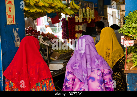 Indian women buying produce at indoor food stall in Singapore Stock Photo
