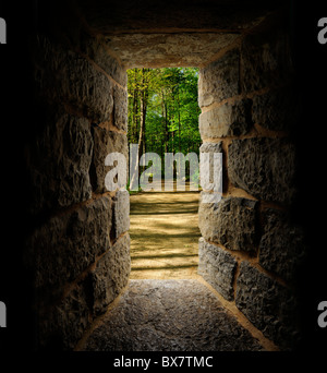 Path through trees as viewed out of a castle-like stone window or passage Stock Photo