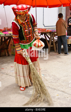 Woman trying out broom in market, Shaxi, Jiangsu, China Stock Photo