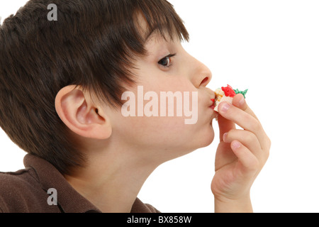 Adorable 7 year old french american boy eating small bakery treat over white background. Stock Photo