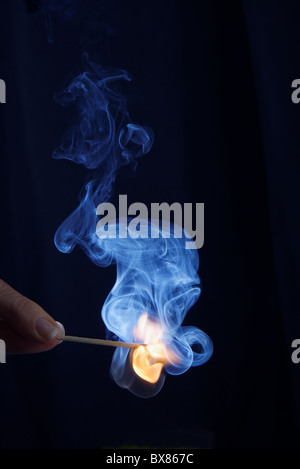 hand holding burning match stick on black background Stock Photo