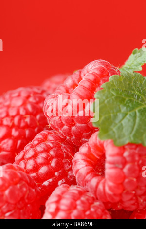 Fresh ripe raspberries with green mint leaves on black plate against ...