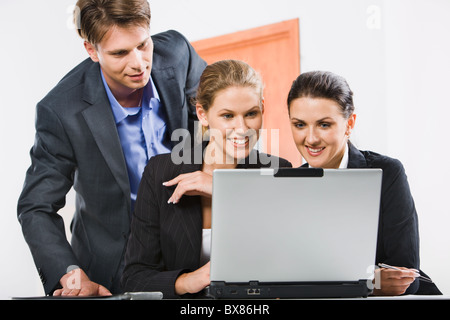 Businessman is looking at computer worked by two colleagues Stock Photo