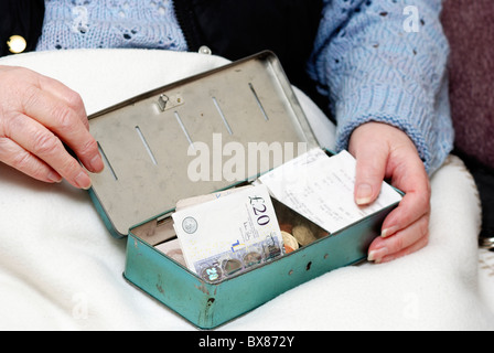 pensioner with cash tin and English currency Stock Photo