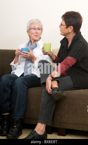 Two senior women drinking coffee, chatting and having a good time together as girl-friends. Stock Photo