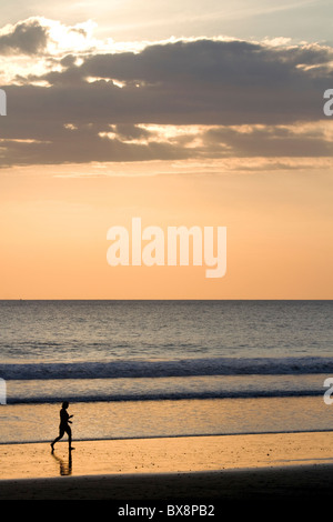 People walk on the beach at sunset in Jaco, Costa Rica. Stock Photo