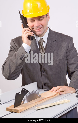 businessman with phone working on an circular saw Stock Photo