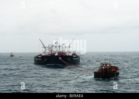 Oil tanker ship anchored in offshore area waiting to be loaded by a production oil rig from petrobras, brazilian oil company. Stock Photo