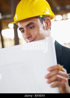 caucasian male architect examining blueprint. Vertical shape, waist up, side view, copy space Stock Photo