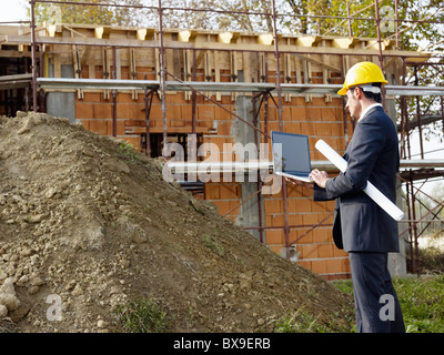caucasian male architect holding laptop computer and scroll. Horizontal shape, three quarter length, side view Stock Photo