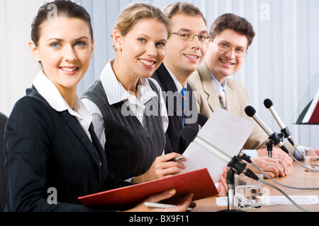 Portrait of four confident professionals sitting at the table and looking at camera Stock Photo