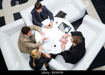 Portrait of businesspeople sitting around at the table and discussing an important questions Stock Photo