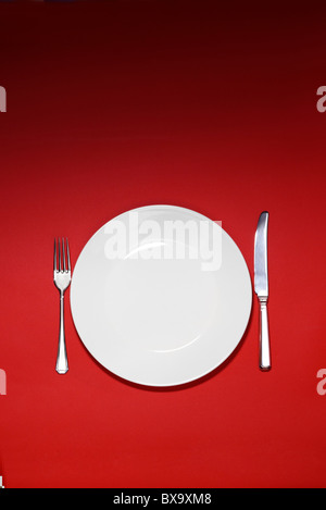 White plate and place setting on a red background Stock Photo
