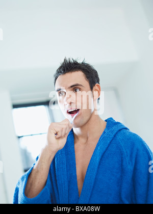 caucasian man brushing teeth in bathrobe Stock Photo