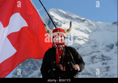 A Swiss fan with real horns , with a big flag,during a ski racing Stock Photo