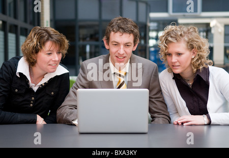 Two businesswomen are shocked by what their male colleague is doing on his laptop... Stock Photo