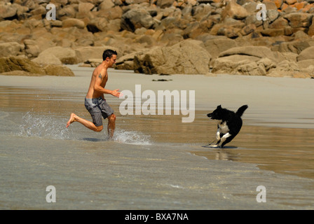 Man playing with his dog on Sennen beach, Cornwall. Stock Photo