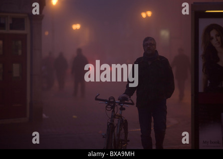 Heavy fog envelops the city center of Ely in Cambridgeshire. It is early evening and people are Christmas shopping. Stock Photo