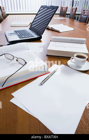 Typical workplace of a busy successful business person in the morning before meeting: computer, books, pens, papers, a cup of co Stock Photo