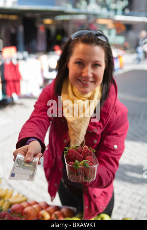 Young woman paying for basket of strawberries Stock Photo