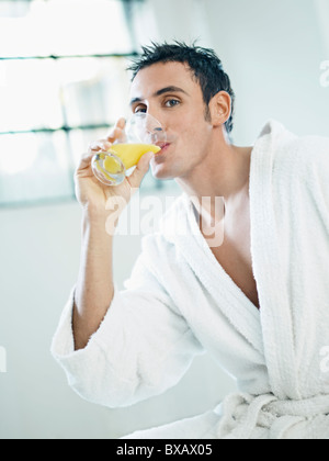 man in bathrobe drinking orange juice Stock Photo