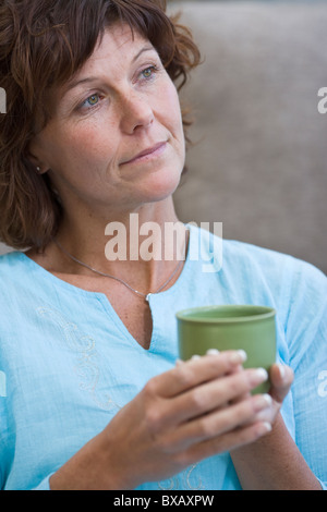 Mature woman holding cup, smiling Stock Photo